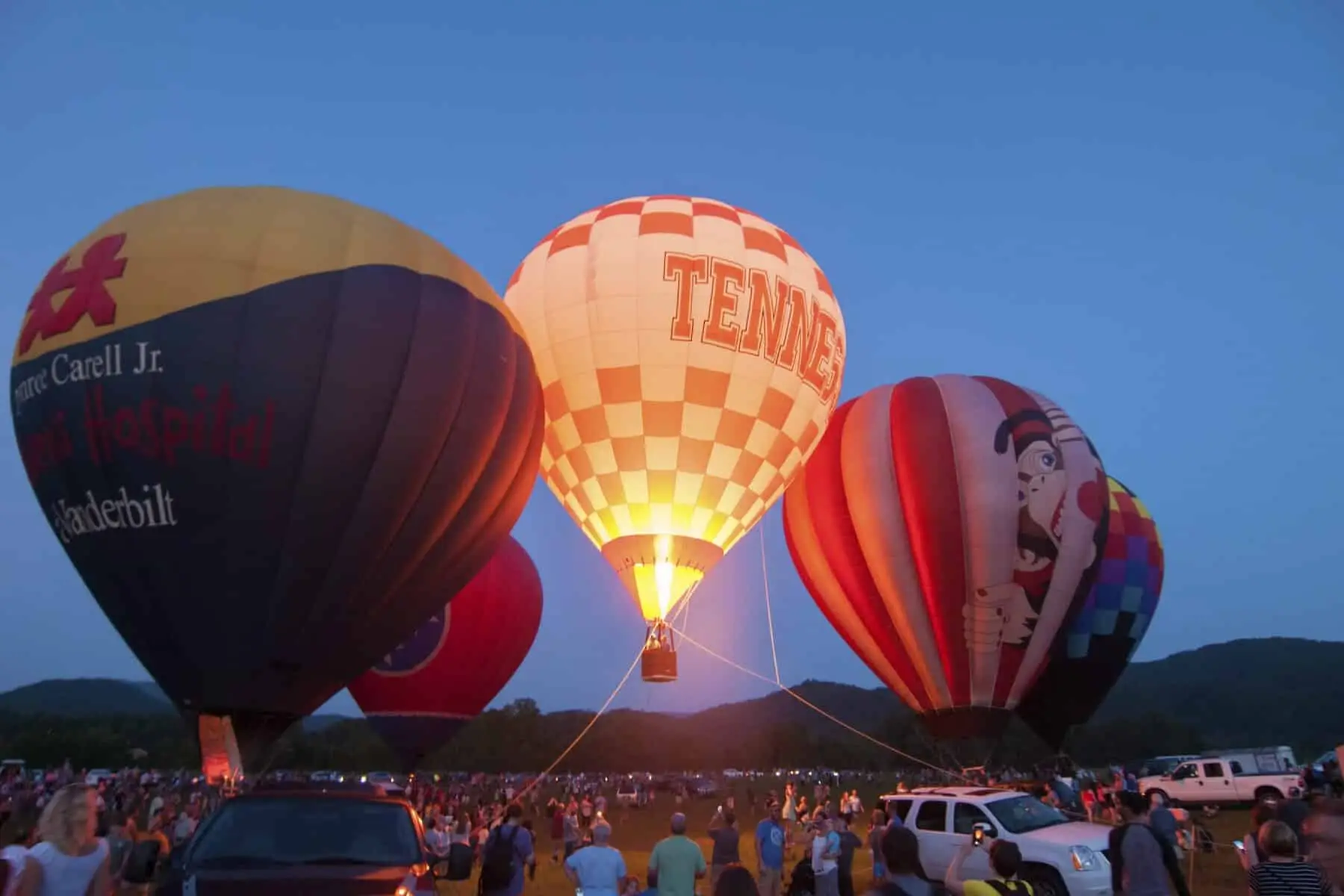 A plethora of large Hot Air Balloons including a large University of Tennessee Hot Air Balloon in a beautiful outdoor sunset in Townsend Tennessee